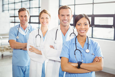 Picture of two male medical professionals and two female medical professionals standing in hospital with arms crossed and smiling.