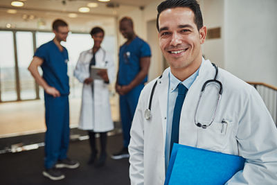 Picture of a male doctor holding a patient chart with three other medical professionals behind him.