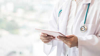 Picture of a male doctor dressed in a white coat, holding a patient chart.