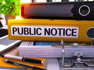 Picture of public notice binders sitting on and desk with pens.